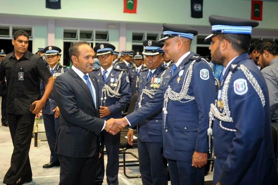 Dr Jameel shaking hands along a line of police officers in white dress uniform with aiguillettes.