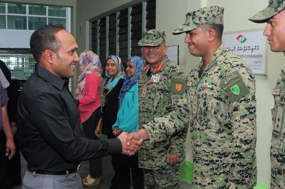 Dr Jameel shaking hands with uniformed personnel in camouflage fatigues at an indoor gathering.