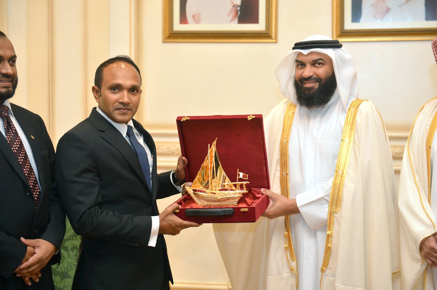 Dr Jameel presenting a model dhoni in a presentation case to a host in traditional dress.