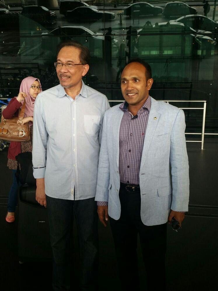 Dr Jameel standing for a photograph beside his host in a modern building.